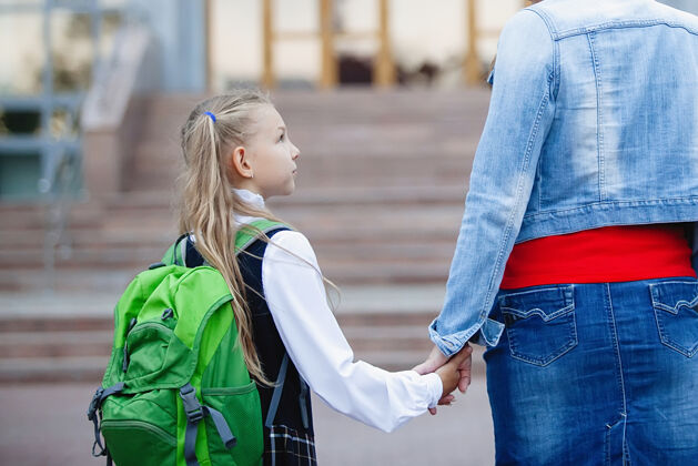 女性十几岁的女学生穿着制服 手里拿着一个背包和妈妈 走在台阶上学校回来查看青少年格子漂亮
