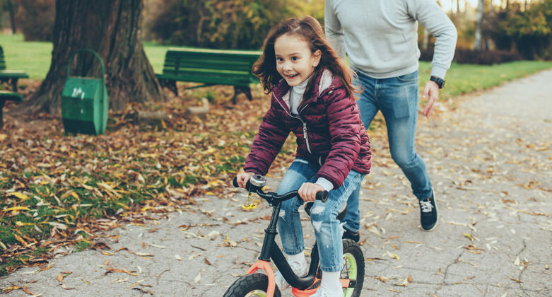 背景可爱的女孩骑着自行车 试图逃离父亲在秋天追她家庭户外女性