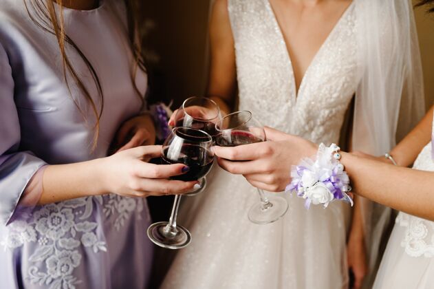 婚礼华丽的新娘和伴娘在婚礼上用酒敬酒 尽情享受早上好手拿着时髦的玻璃杯 喝着饮料 叮当作响酒杯女性干杯