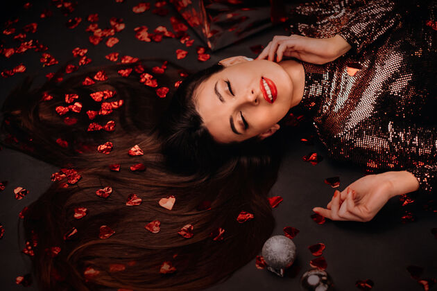 谎言俯视图中 一个女孩穿着闪亮的衣服躺在地板上 五彩纸屑以心形出现乐趣情人节新的
