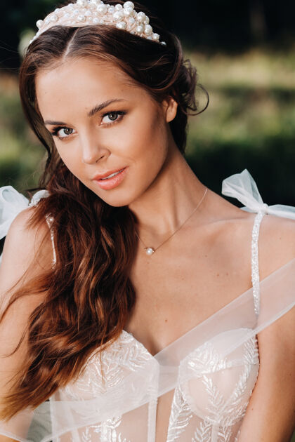 微笑一个穿着白色裙子的优雅新娘在自然公园里的特写镜头风景新娘水