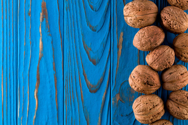 成熟整个胡桃树在漆成蓝色的木桌上的俯视图碗分散果壳