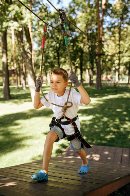 学校小男孩在绳索公园里攀爬男性操场树