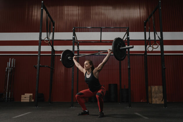 举重女强人把杠铃举过头顶 做什么健身操年轻女子在健身房举重运动员身体力量
