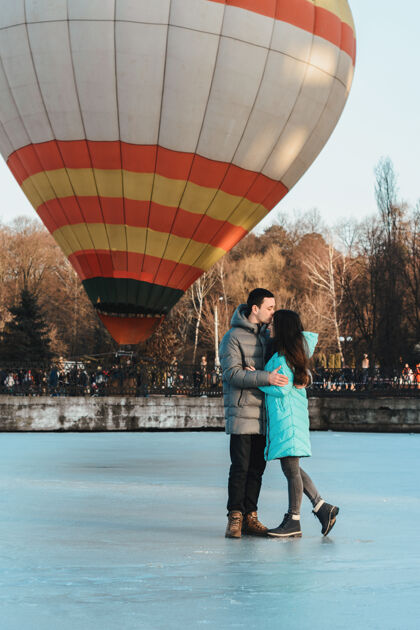 热新娘和新郎在冰冻的湖面和城市公园里飞行的气球的背景下天空目的地壮观