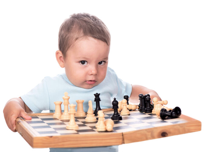 微笑快乐的男孩与棋盘隔离在白色背景上男性乐趣棋盘