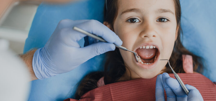微笑特写镜头：一个漂亮的小女孩坐在口腔科的座位上 接受儿科口腔医生的牙齿检查医生牙痛男人