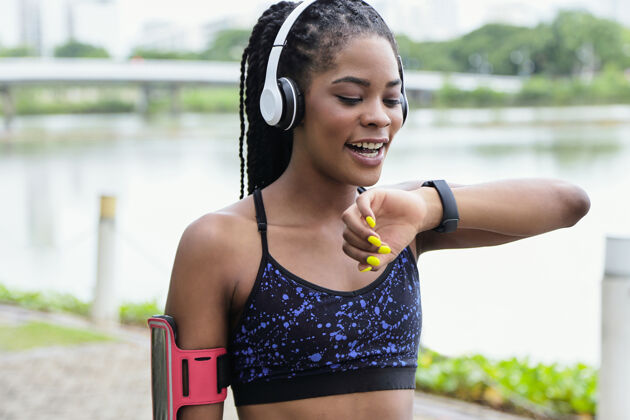耳机在公园训练时 年轻漂亮的女运动员通过智能手表为朋友录制语音信息肖像运动黑人