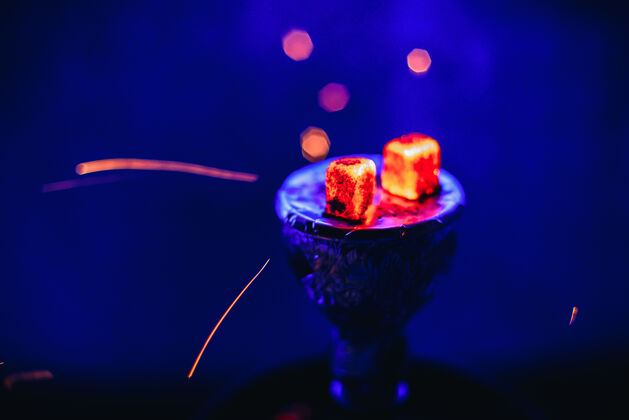 土耳其水烟与发光的红色余烬和飞溅的火花在蓝色背景碗发光光尼古丁