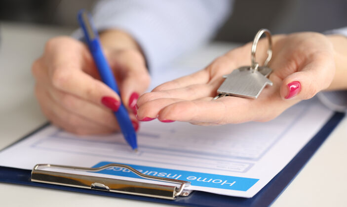 清洁女性的手拿着房屋钥匙 填写房产财产保险保险理念协议租金手