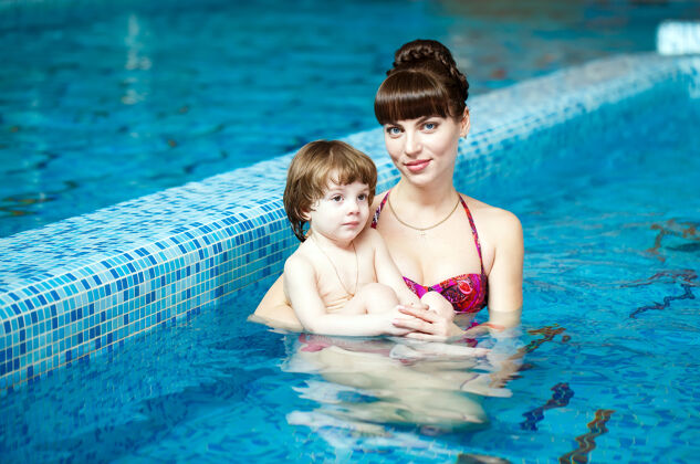 水妈妈教孩子在游泳池里游泳人小健康