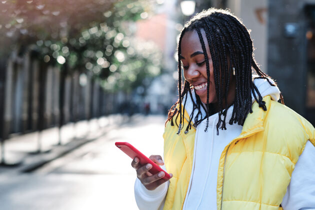 年轻人一位非洲裔美国妇女在户外用手机微笑街道.城市以及沟通理念站着个人通信