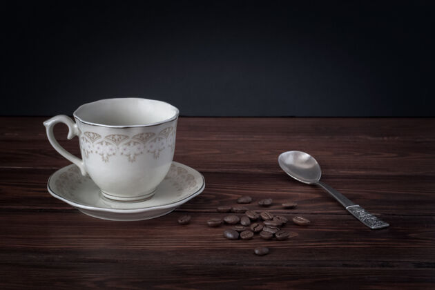 早餐茶碟上的空咖啡杯 深色桌板上的银匙咖啡豆咖啡茶时间饮料