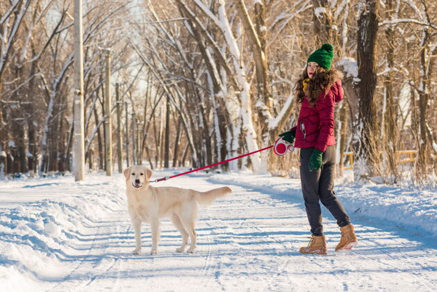 拉布拉多冬季公园里的一位年轻女子和她的金毛猎犬散步的画像乐趣户外玩