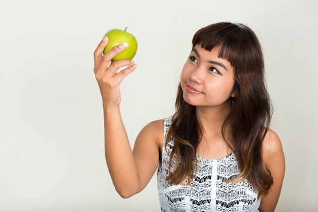 思考年轻漂亮的亚洲女人对抗白色空间头发染色苹果