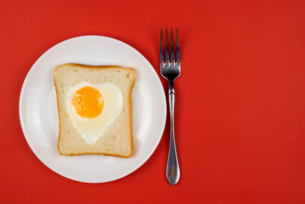 吐司白色陶瓷上烤黑麦面包片中的心形鸡蛋瓦伦丁牌情人节概念爱情早餐设计.自制健康的三明治喜庆的午餐或早餐收到空间自制早餐健康