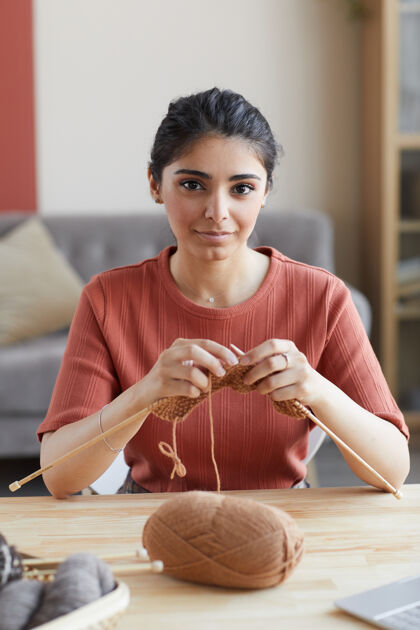 坐着一幅年轻女子坐在桌前 在家里用针编织的画像成人针刺绣