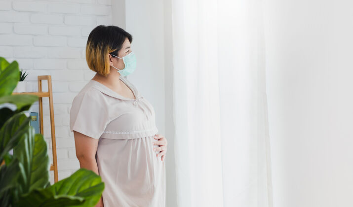 妈妈亚洲孕妇戴上防护口罩以防细菌预防窗户女人