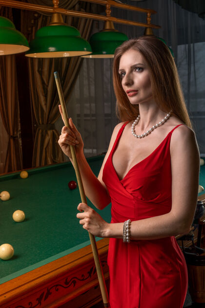 女人年轻优雅的女士拿着球杆站在台球桌旁球台球桌时尚