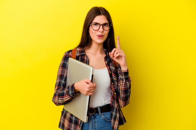 成功年轻的白人女学生拿着一台笔记本电脑 背景是粉红色的 她有一些伟大的想法 创意的概念教育学习学习者