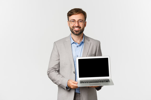 情绪笑容可掬的帅哥商人画像和眼镜 演示笔记本电脑屏幕笔记本电脑时尚老板