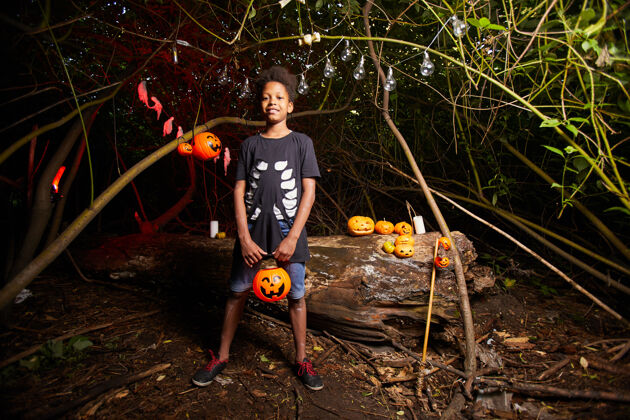 橙色在黑暗的户外参观万圣节派对时非洲男孩的画像叶子运动季节