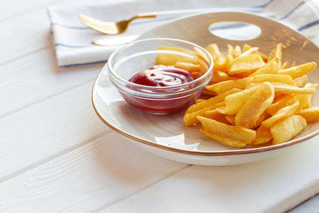 番茄酱放在木桌上的带酱汁的炸薯条土豆盘特写烹饪卡路里快餐