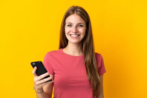 手势年轻女子用手机孤立的黄色笑了很多成人乐趣手机