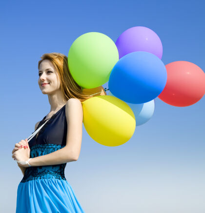 绿色红发女孩带着彩色气球在蓝天上天空黄色户外