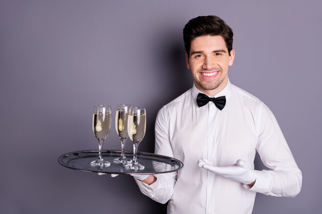 托盘这是你的订单号：正兴高采烈的服务员端来客人的酒 站在托盘上展示点酒 手穿白衬衫制服 手套隔着灰色的墙微笑杯子优雅