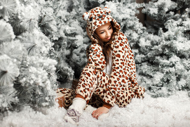乐趣快乐可爱的女孩穿着时髦的熊睡衣坐在圣诞树旁人漂亮房子