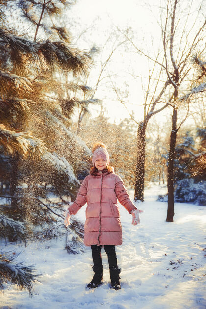 下雪小女孩在阳光明媚的冬日里玩得很开心帽子游戏森林