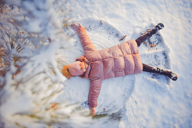 寒冷小女孩在阳光明媚的冬天玩得很开心白天下雪天使的姿势五颜六色可爱童年