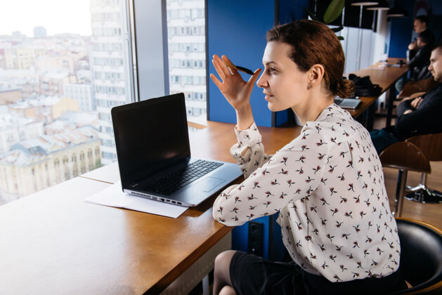 女性富有创意的商务女性在城市景观的明亮办公室里用笔记本电脑和智能手机工作记者室内通信