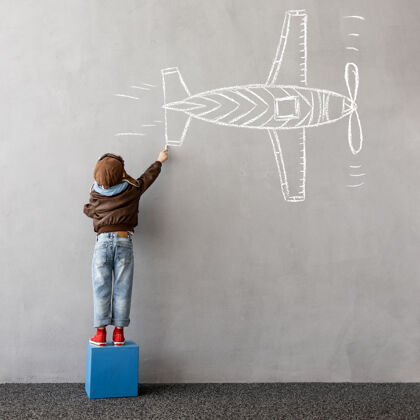 自由梦想大快乐的孩子在墙上画一架粉笔飞机粉笔冒险飞行