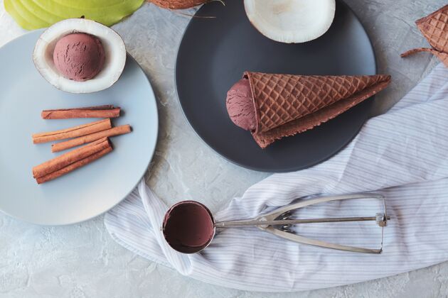 香料自制的巧克力冰淇淋在华夫蛋卷上 椰子放在浅色的桌子上食物蛋卷健康