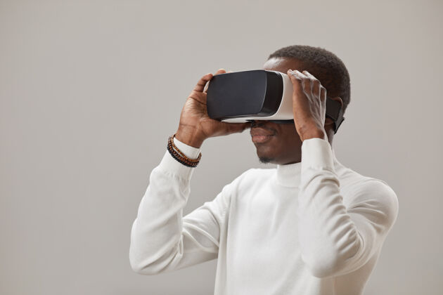 腰向上戴着虚拟眼镜的年轻人在玩虚拟现实游戏对抗灰墙创新发现微笑