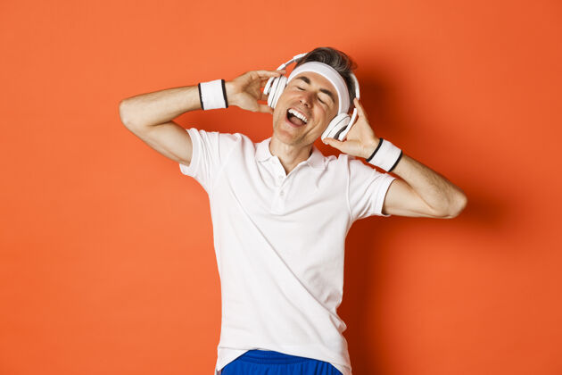 表情无忧无虑的中年男运动员画像 戴着耳机听音乐站成人帅气