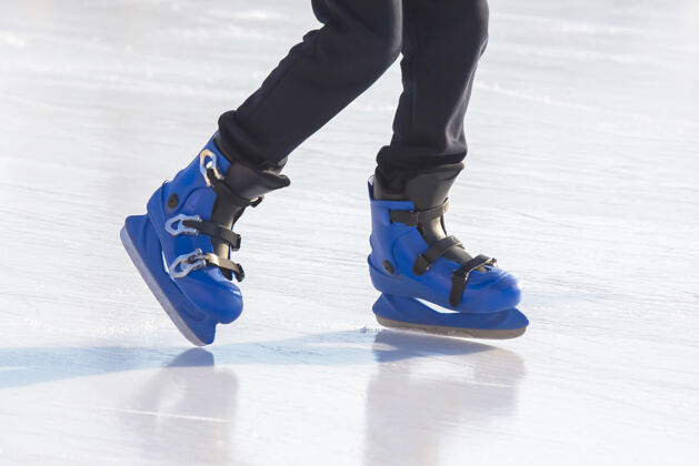 健身一个穿着蓝色溜冰鞋的人的腿骑在溜冰场上健康冷冻鞋