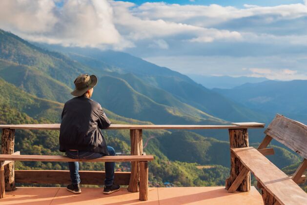 云快乐的旅行者坐在山顶上看风景户外自然风景