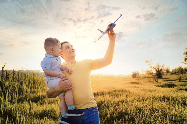 高加索快乐的父亲和儿子玩玩具飞机梦想当飞行员男人团聚户外