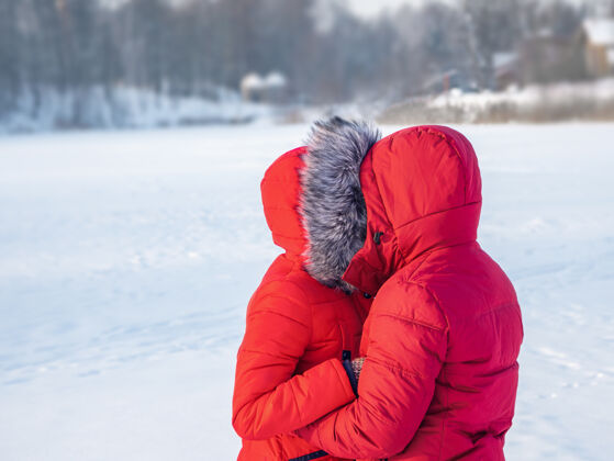 成人冬天一对穿红色夹克的情侣在寒冷中拥抱乐趣年轻关系