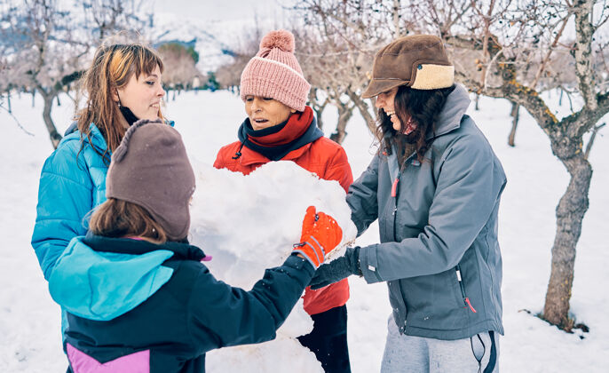 雪人四个戴着手套的白人女孩喜欢堆雪人快乐户外快乐