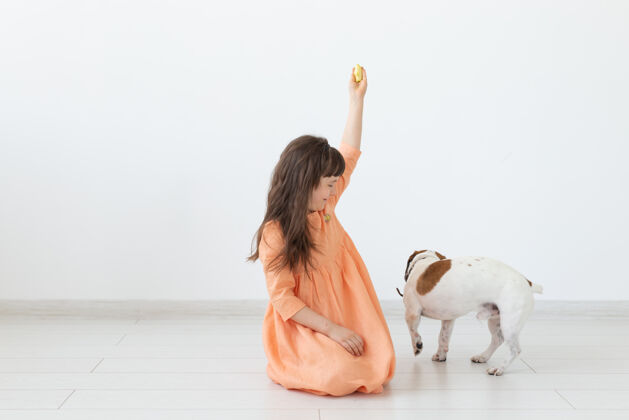 孩子宠物 儿童和狗的概念-小女孩穿着衣服玩小狗罗素放松杰克