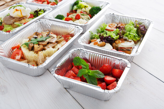 桌子浆果甜点和其他菜餐厅交货甜草莓沙拉铝箔盒在白木健康食品外卖品种水果有机