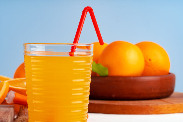 稻草桌上放着一杯橙汁和红麦杆美味多汁果汁