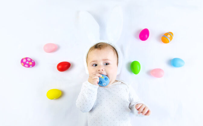 手宝宝穿得像兔子 在白色的表面上放复活节彩蛋表情肖像玩