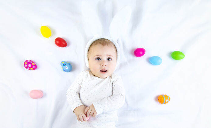 服装宝宝穿得像兔子 在白色的表面上放复活节彩蛋鸡蛋兔子童年