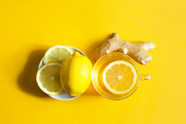 茶杯药茶一杯 生姜 柠檬 增强免疫系统在寒冷的季节维生素饮料的健康和黄色照明背景上的成分复制空间 平提神恢复能量