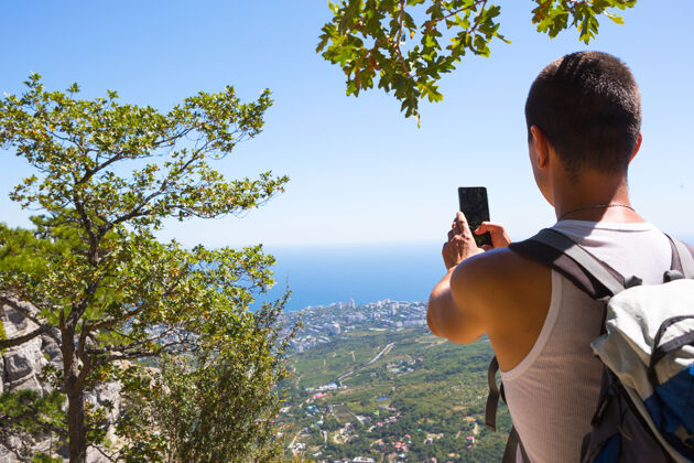 网络男游客用智能手机拍摄山区美丽的海景远足通信针叶树